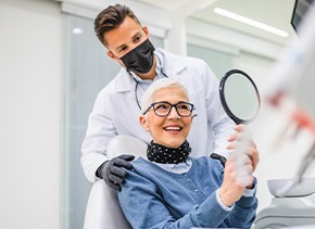 Woman smiling at reflection in handheld mirror