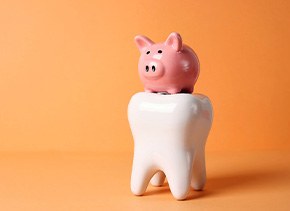 a model tooth with a piggy bank resting on top