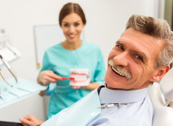 older man in dental chair learning about dentures in Brooklyn 