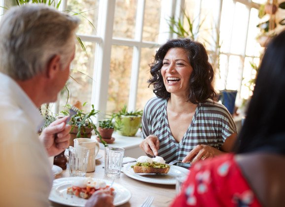 Woman smiling while eating at restaurant with friends