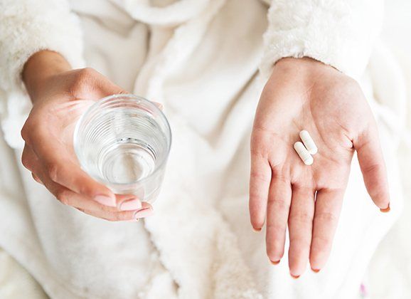 Patient holding glass of water and antibiotic pill