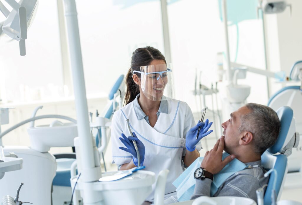 Smiling dentist talking to patient during exam